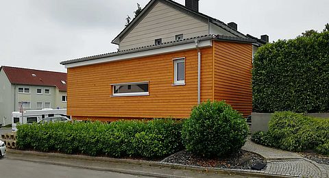 eingeschossiger Anbau an ein Wohnhaus mit Holzfassade
