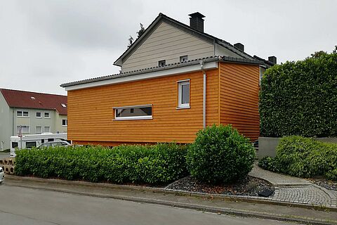 eingeschossiger Anbau an ein Wohnhaus mit Holzfassade