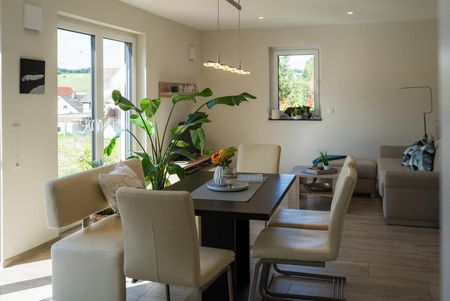Offener Wohn- und Essbereich mit hellem Boden, modernen Möbeln und großem Fenster im Einfamilienhaus Lichtenau