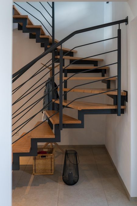 Offene Treppe aus Holz und Metall mit schlichtem Geländer in einem modernen Einfamilienhaus in Lichtenau