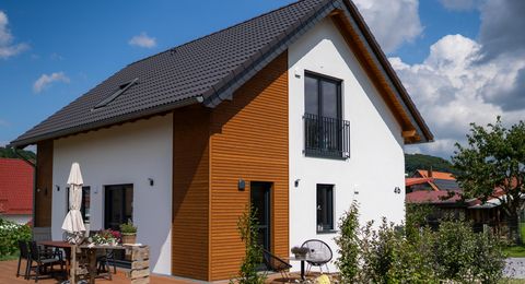 Terrasse mit Blick auf das Einfamilienhaus in Lichtenau Sonnige Terrassenseite des Einfamilienhauses in Lichtenau mit gemütlicher Sitzgruppe, Holzfassade in Rhombusprofil und weiß verputzter Hauswand