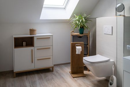Helles Badezimmer mit Dachfenster im Einfamilienhaus Lichtenau, ausgestattet mit wandhängendem WC, Naturtönen, Pflanzen und viel Tageslicht